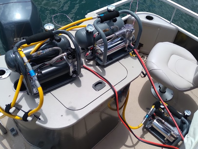 Scuba tanks and equipment on a boat, surrounded by clear blue water.